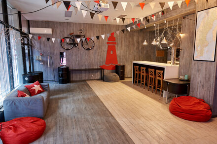 Стильный лофт в скандинавском стиле. Вход с улицы. Красные пуфики, серое кресло.