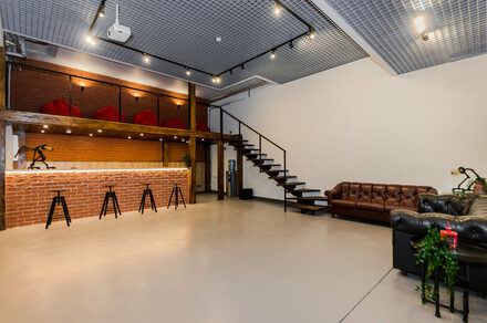 Стильный двухуровневый лофт. Барная стойка. Лестница на второй этаж. Пуфы. Диваны. Барные стулья