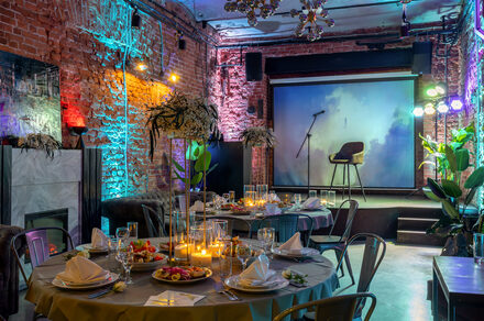 Лофт со сценой. Хорошо освещённый лофт. Диваны. Столик. Камин. Сцена с микрофоном