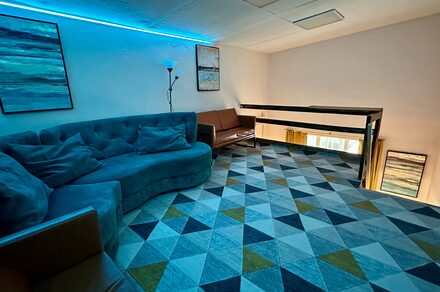 Яркий двухуровневый лофт. Второй этаж лофта. Голубое освещение. Угловой диван. На стенах картины