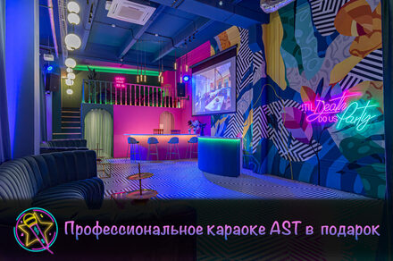 Лофт Май. Зал Мира. Караоке-зал с яркими стенами в абстрактных узорах, неоновая надпись, барная стойка с высокими стульями, черный диван, черно-белый полосатый пол, большая проекция на стене, подвесные круглые светильники, розовая барная зона под лестницей. Текст: "Профессиональное караоке AST в подарок".