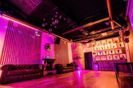 LoftForParty (ЛофтФорПати). Бэкстейдж лофт . Тёмное помещение с низким потолком, кожаные диваны, барная стойка, разноцветное освещение, стены отделаны деревянными панелями и кирпичом, металлические трубы на потолке, зеркальный декор, дискоболы, деревянный пол.