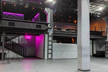 PRAVDA(Правда). Просторный зал на 800 гостей. Большое закрытое пространство с бетонным полом и высокими потолками, многоуровневое с лестницей, балкон. Есть знак "WC" с неоновой подсветкой, освещение в виде точечных светильников. Стены серые, чёрные деревянные и металлические элементы.