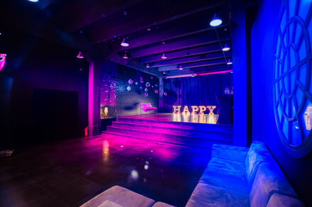 Стильный панорамный лофт на Петроградке. Улыбающийся мужчина, позирующий на камеру. На заднем плане дургие люди общаются