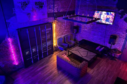 Контраст Loft. Приглушённый свет. неоновая подсветка. Барная стойка с барными стульями. Кресла. Картина на стене. Декоративные свисающие лампы