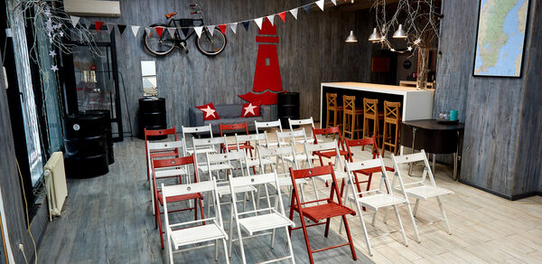 Стильный лофт в скандинавском стиле. Вход с улицы. Сладные стулья в формате конференции, вид зала со сцены.