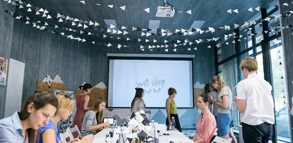 Стильный лофт в скандинавском стиле. Вход с улицы. Накрытый банкетный стол на фоне большого экрана. Люди на празднике.