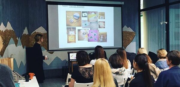 Стильный лофт в скандинавском стиле. Вход с улицы. Люди на конференции смотрят на большой экран.