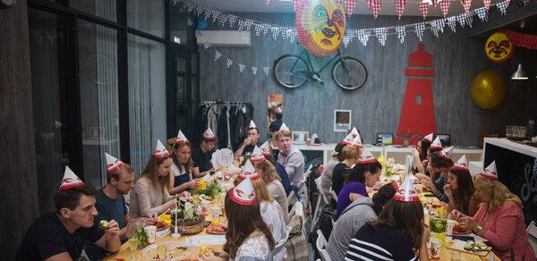 Стильный лофт в скандинавском стиле. Вход с улицы. Праздничный стол на день рожденья, гости в бумажных колпаках.