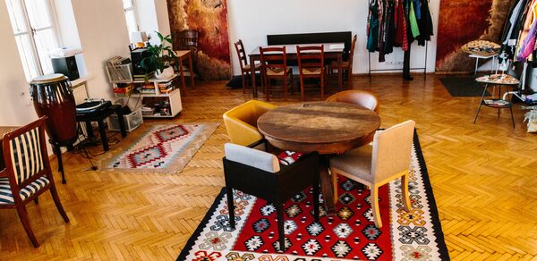 Светлый лофт с панорамным видом. Столы со стульями. Ковры на полу. Различные элементы декора. Вешалки