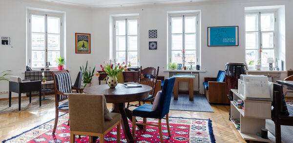 Светлый лофт с панорамным видом. Столы со стульями. Ковры на полу. Различные элементы декора