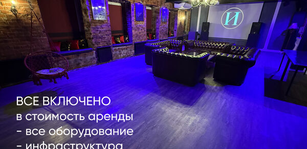 Лофт ИЗНАНКА. Зал КАСТЛ. Пространство с кирпичными стенами, фиолетовая подсветка, деревянный пол. В центре кожаные диваны, стол, проектор с экраном. Потолочные светильники, кресло-качалка, барные стулья. Текст: «Все включено в стоимость аренды - все оборудование - инфраструктура - работа администратора».