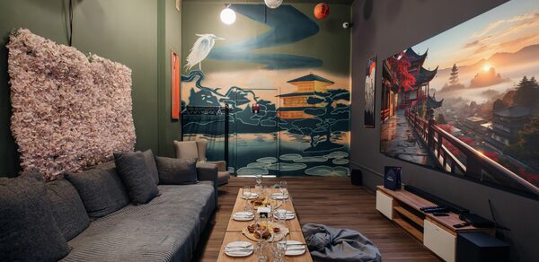Rubin Loft (Рубин Лофт). Зал Китай. Караоке-зал с диваном и креслом у стены в зелёных тонах, настенной росписью с азиатскими мотивами, столом с закусками и напитками, пуфом. Большой экран с изображением природы, мягкое освещение потолочными светильниками, деревянный пол.