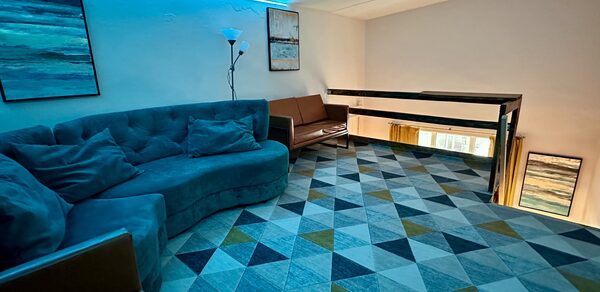 Яркий двухуровневый лофт. Второй этаж лофта. Голубое освещение. Угловой диван. На стенах картины