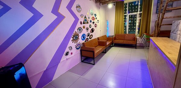 Яркий двухуровневый лофт. Разукрашенные стены с рисунками. Диваны. В углу колонка. Барная стойка