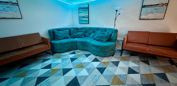 Яркий двухуровневый лофт. Второй этаж лофта. Голубое освещение. Угловой диван. На стенах картины