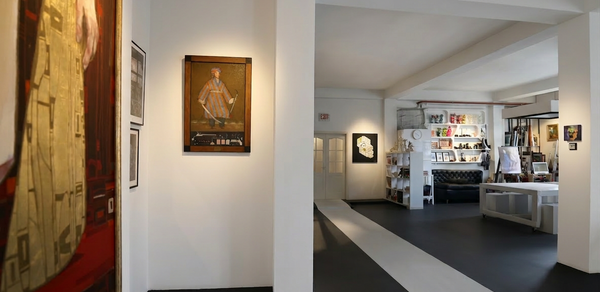 А53: Secret Gallery (Секретная галерея). Галерейное пространство с белыми стенами и черно-белым полом. Картины на стенах. Черный диван и стол в зоне отдыха, стеллажи с книгами справа. Яркое искусственное освещение. Открытая планировка с видимой мебелью и декором.