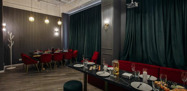 Rubin Loft (Рубин Лофт). Лофт Вегас. Пространство для мероприятий с серыми стенами и высоким потолком. Красные стулья и диваны вокруг темных деревянных столов с тапас и напитками. Подвесные и настенные светильники, тёмно-зелёные шторы, деревянный пол, зеркальный шар под потолком.