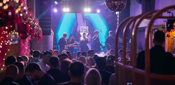 Бар StereoPeople (СтереоПипл). Клубное пространство с живой музыкой, сцена с исполнителями, красочная светодиодная подсветка, зеркальный шар на потолке, декорации с гирляндами и красными шарами, гости в зале, надпись на экране «STEREO PEOPLE».