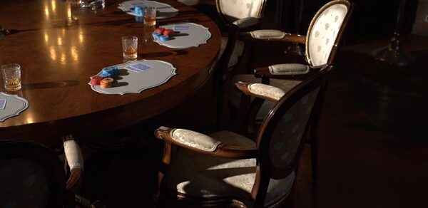 Polygon(Полигон). Зал Апартаменты. Круглый деревянный стол с набором кружевных подставок, на них стаканы и разноцветные плотные кружки. Вокруг стола стоят классические стулья с подлокотниками и светлой обивкой. Освещение теплое, направлено сверху. Пол тёмный.