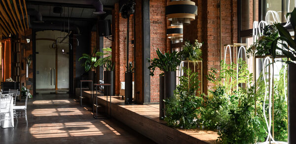 Zafferano Loft(Зафферано лофт). Лофт-пространство с кирпичными стенами, большими окнами, деревянным полом и черным потолком. Присутствуют растения в металлических стойках, подвесные светильники и белые стулья. Естественное освещение.