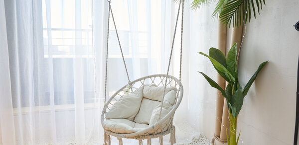 Лофт Мальдивы с открытым душем, балконом и видом на Сити. Подвесное кресло-кокон с подушками, окружённое белыми гальками. Прозрачные шторы, пропускающие свет. Около стены растение в горшке, за креслом бамбуковый стебель. Светлая цветовая гамма, деревянный пол.