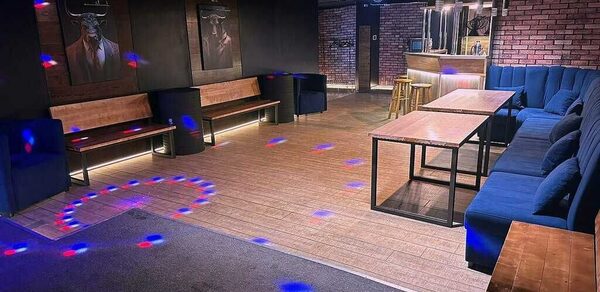 BULL LOFT(Лофт Бык) . Лофт-пространство с деревянным полом, зонами для отдыха с синими и деревянными диванами, несколькими прямоугольными столами, барной стойкой из светлого дерева, барными стульями. Кирпичные стены, картины, дискотечное освещение с цветными точками.