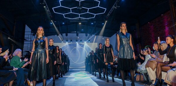 Studio Hall(Студио Холл). Показ мод в просторном помещении с высоким потолком. Подиум для моделей окружён зрителями. Люстры в виде шестиугольников и прожекторы обеспечивают освещение, стены из красного кирпича. Платья моделей черного и синего цвета.