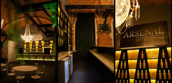 Arsenal Loft(Арсенал Лофт). Лофт-пространство с кирпичными стенами и арочными потолками. Зона барной стойки с деревянными столешницами, полки с декоративными бутылками. Круглый стол и стулья. Крупная хрустальная люстра. Надпись "LOFT & CATERING". Теплое освещение.