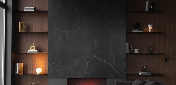 Зал Black. Фотостудия Мимика. Гостиная с тёмной каминной зоной, большая чёрная плита. Открытые полки с книгами и декором. Угольная мебель, мягкий диван. Лампы тёплого света, стеклянный столик с бокалами. Отделка тёмного дерева, окно слева.