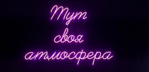 Лофт «Блэкберри». Неоновая надпись «Тут своя атмосфера» розового цвета на черном фоне.