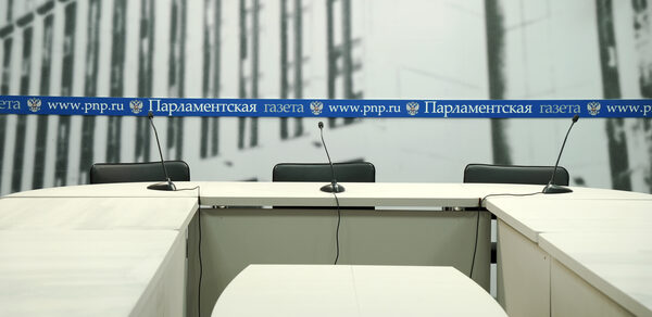 Конференц-зал до 60 гостей площадью 150 м². Пространство для конференций с тремя белыми столами, черными креслами и микрофонами. Задний план с черно-белой графикой здания и синим баннером с текстом «www.pnp.ru Парламентская газета».