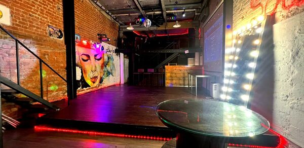 Soul Loft . Крупный план угла большого зеркала и гирлянд на ней, всё расположено у кирпичной стены