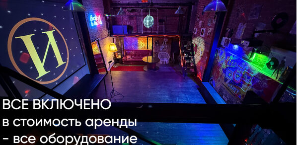 Лофт ИЗНАНКА. Зал ЛИХИЕ 90-е. Затемнённая комната лофта, много людей в кадре проводят фуршетное мероприятие, беря еду с объединённых столов. Несколько людей на кадре танцуют