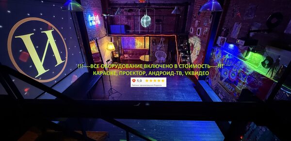 Лофт ИЗНАНКА. Зал ЛИХИЕ 90-е. Гостиное пространство с кирпичными стенами. Подвесные светильники и разноцветная подсветка. Лестница, мягкие стулья, проектор. Неоновая вывеска и текст: «Все оборудование включено в стоимость: караоке, проектор, Андроид-ТВ, ВКвидео».