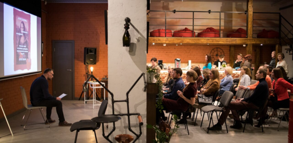 Стильный двухуровневый лофт. Человек ведёт лекцию. Слушатели смотрят на экран и лектора