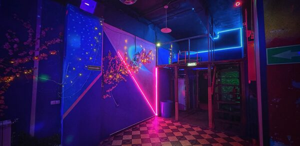 Лофт в стиле Диско. Танцевальная зона с шахматным полом, неоновыми огнями на стенах и диско-шаром на потолке. Синие, розовые и фиолетовые оттенки. Украшение искусственными цветами. Металлическая конструкция с лестницей в уголке. Световое оформление с использованием линий.