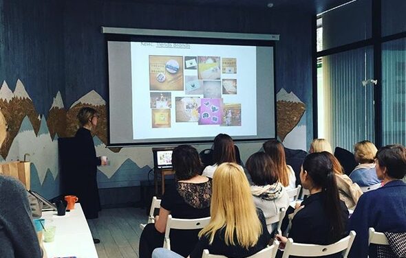 Стильный лофт в скандинавском стиле. Вход с улицы. Люди на конференции смотрят на большой экран.