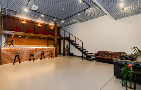 Стильный двухуровневый лофт. Барная стойка. Лестница на второй этаж. Пуфы. Диваны. Барные стулья