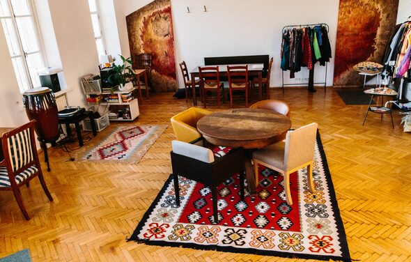 Светлый лофт с панорамным видом. Столы со стульями. Ковры на полу. Различные элементы декора. Вешалки