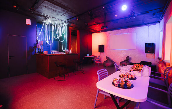 Лофт Santa с большими окнами. Белые столы, стулья. Экран. Пуфы. Колонки. Барная стойка