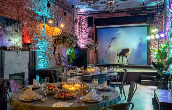 Лофт со сценой. Хорошо освещённый лофт. Диваны. Столик. Камин. Сцена с микрофоном