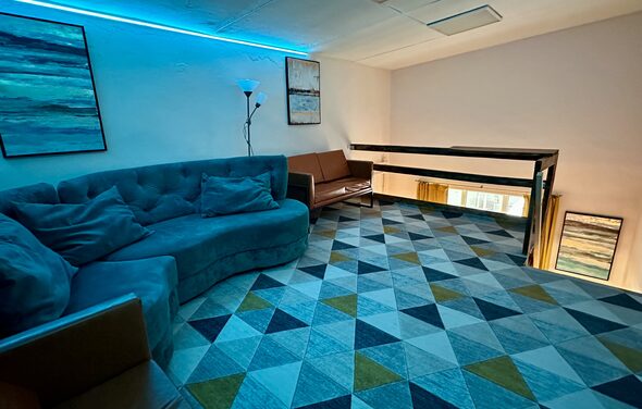 Яркий двухуровневый лофт. Второй этаж лофта. Голубое освещение. Угловой диван. На стенах картины