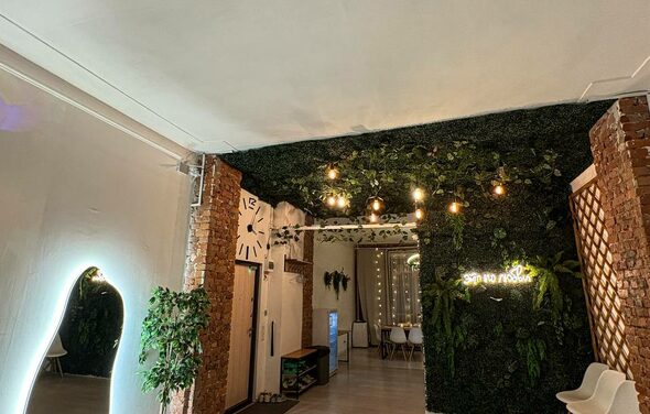 White Loft(Белый лофт). Уютный светлый лофт . Современное пространство с кирпичными и зелеными стенами, подвесные светильники, белые пластиковые стулья, украшенные растениями поверхности, декоративное зеркало с подсветкой, деревянные элементы, светлый пол, неоновая открытка.