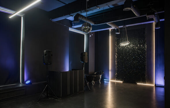 Rubin Loft (Рубин Лофт). Лофт Блэк. Тёмное помещение с черными стенами и потолком, оснащённое светодиодным освещением, подвесным круговым светильником и зеркальным шаром. На полу черные колонки на стойках и черная ванна. Стены украшены вертикальными светодиодными полосами.