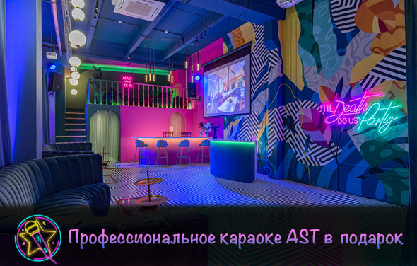 Лофт Май. Зал Мира. Караоке-зал с яркими стенами в абстрактных узорах, неоновая надпись, барная стойка с высокими стульями, черный диван, черно-белый полосатый пол, большая проекция на стене, подвесные круглые светильники, розовая барная зона под лестницей. Текст: "Профессиональное караоке AST в подарок".
