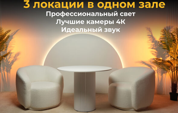 Лофт Восторг. Современное помещение с двумя белыми креслами и круглым столом. Задний план подсвечивается оранжевыми прожекторами. На стене текст: "3 локации в одном зале. Профессиональный свет. Лучшие камеры 4К. Идеальный звук." По бокам искусственные пальмы.