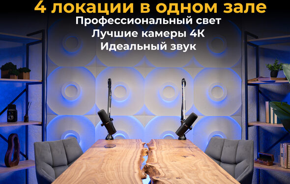 Лофт  Эйфория. Пространство с деревянным столом и двумя микрофонами на стойках. Стена с геометрическим узором и подсветкой. Серые кресла по бокам стола. Полки с книгами и декоративными элементами по бокам. Текст на стене на русском языке.