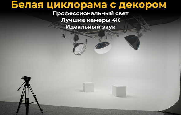 Лофт Циклорама. Белая циклопорама с двумя кубами, установлены три студийных осветительных прибора на потолочной конструкции, штатив. Текст на черном фоне: "Белая циклопорама с декором, Профессиональный свет, Лучшие камеры 4К, Идеальный звук".