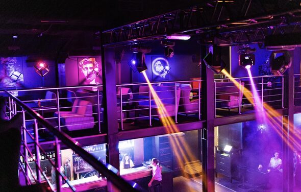 Castle Concert Hall(Концертный зал Замок). Двухуровневое пространство с металлическими перилами, пуломанами и барной стойкой; фиолетовое и розовое освещение; стены декорированы портретами; на верхнем уровне зоны для отдыха; видны световые эффекты.